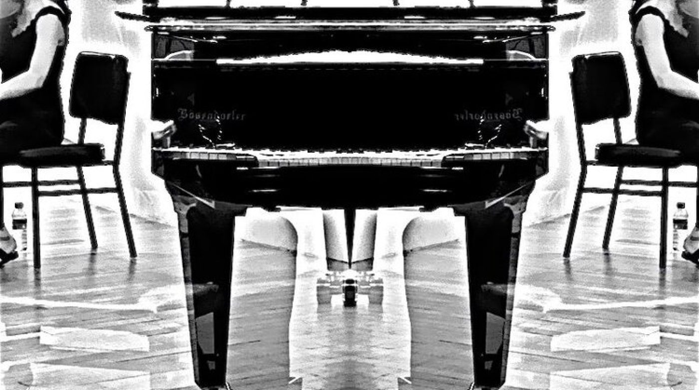 a black and white photo of a woman sitting at a piano.