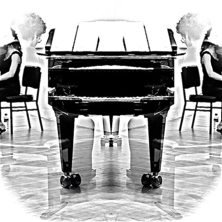 a black and white photo of a woman sitting at a piano.