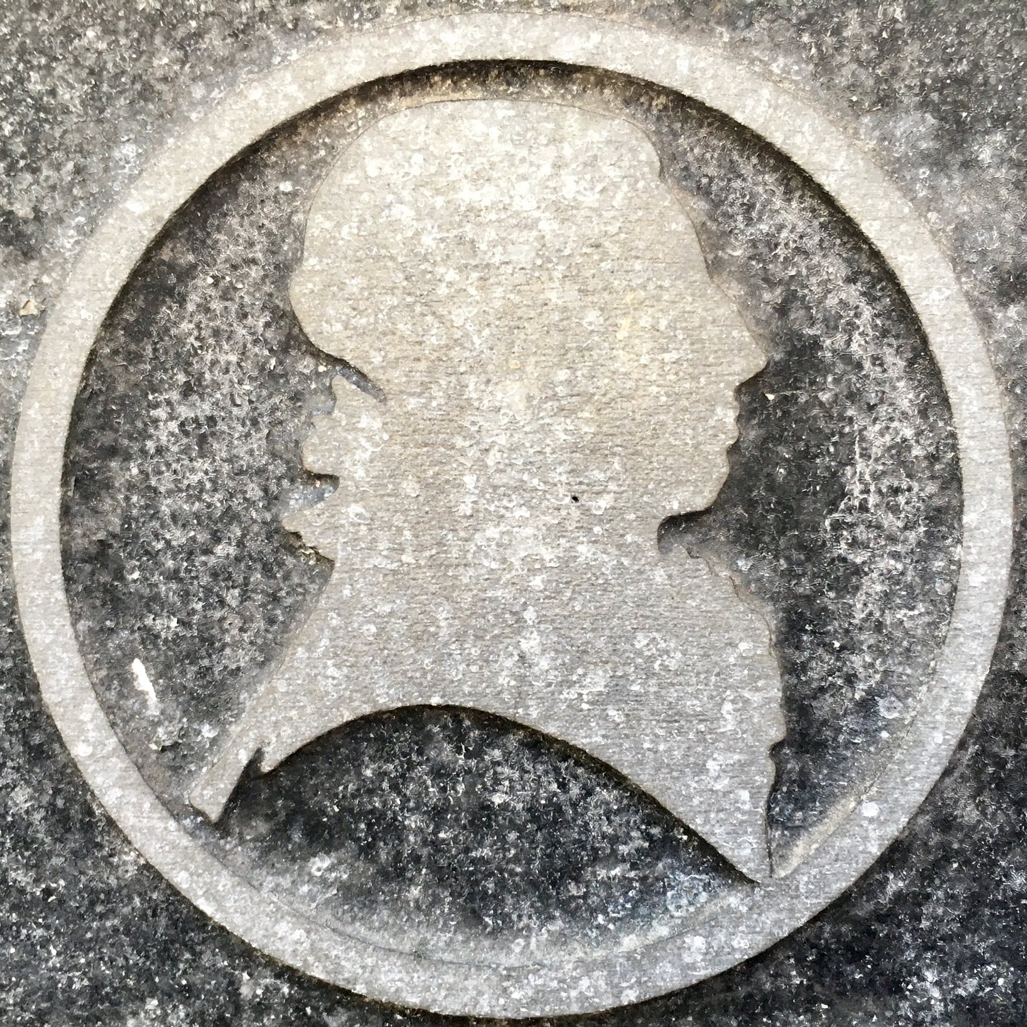 a circular metal sign with a woman's profile on it.