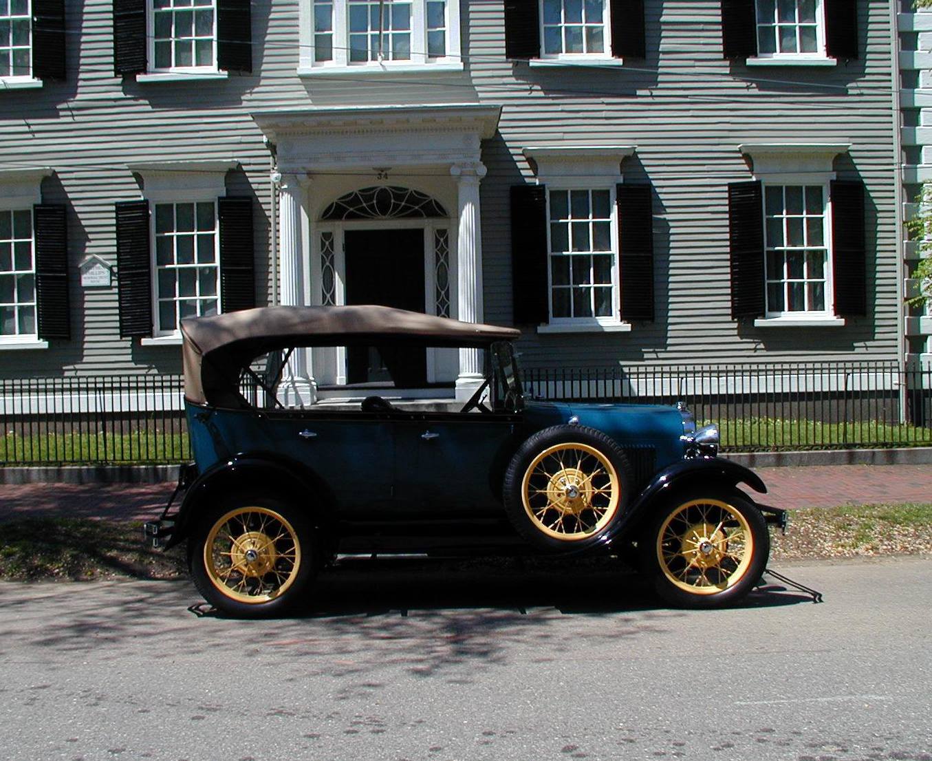 an old car parked in front of a large house.