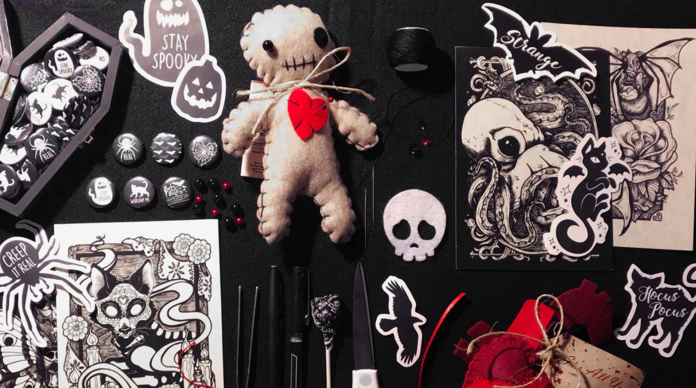 Discover our Halloween collection at Bats in the Belfry Crafts. Unearth a sinister voodoo doll, spooky illustrations, unique buttons, and eerie black ribbons. Plus, explore peculiar scissors and decorative cards—all beautifully arranged on a dark backdrop. Perfect for adding a haunting touch to your seasonal decor!