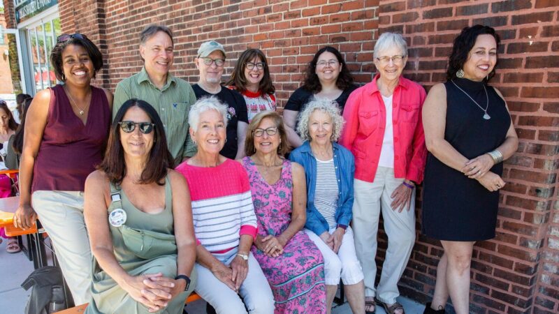 a group of people standing next to a brick wall.