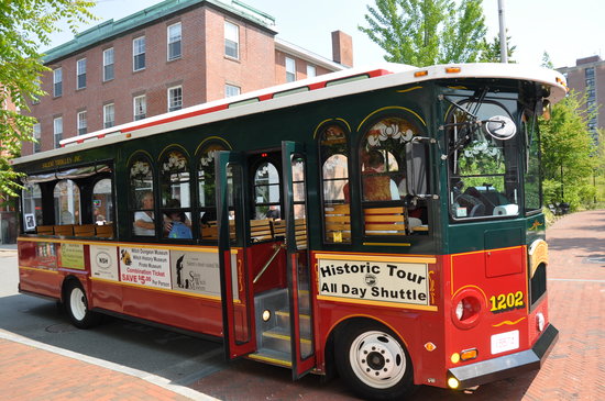 the salem trolley reads "historic tour and all day shuttle." it is red at the bottom and green on top