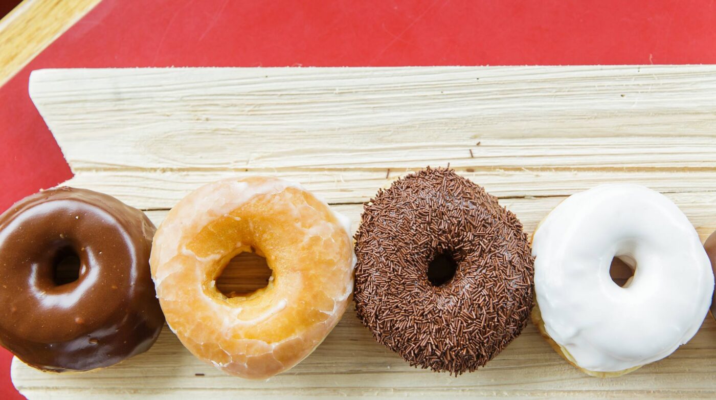 a row of donuts sitting on top of a wooden board.