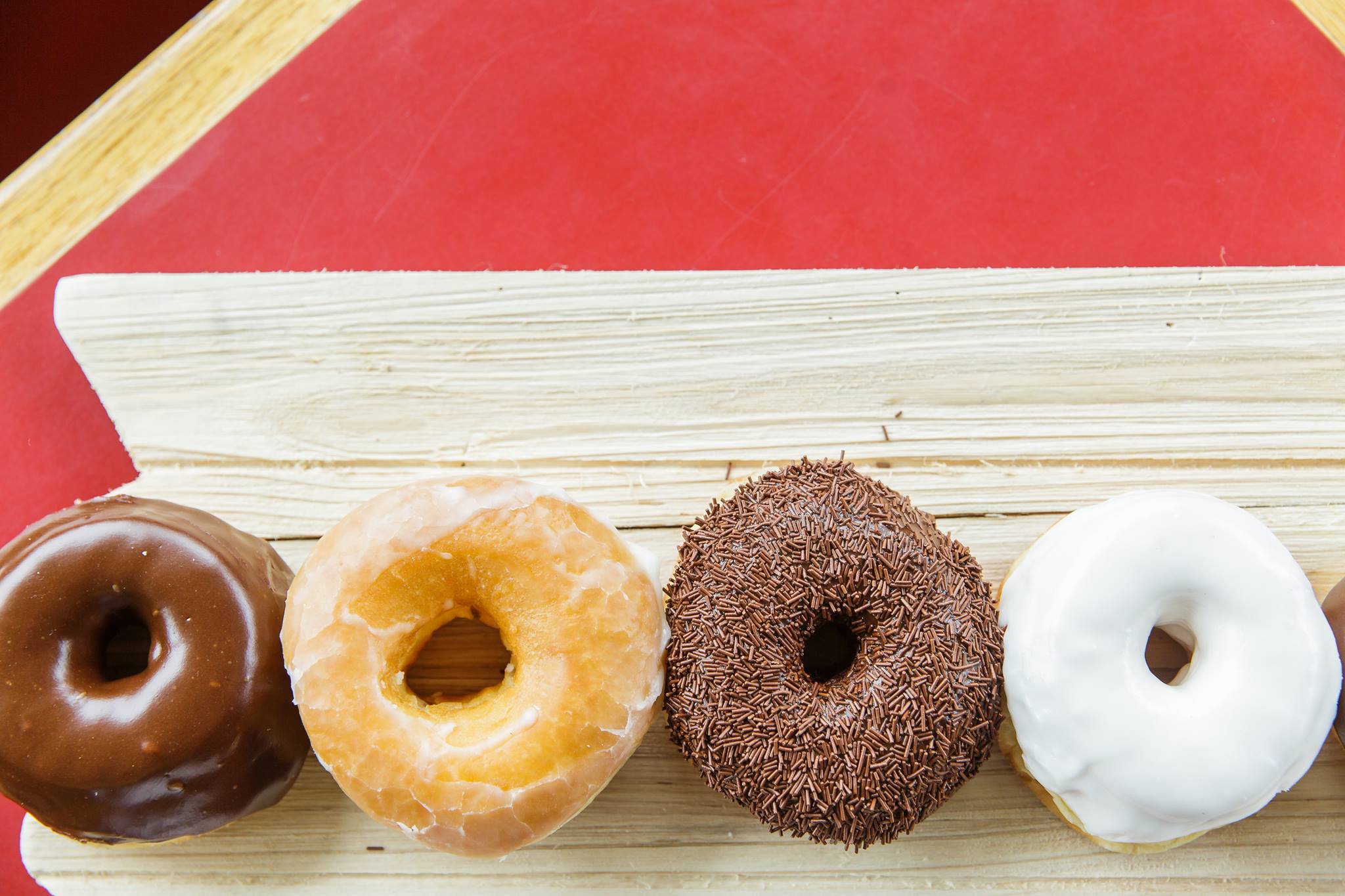 a row of donuts sitting on top of a wooden board.