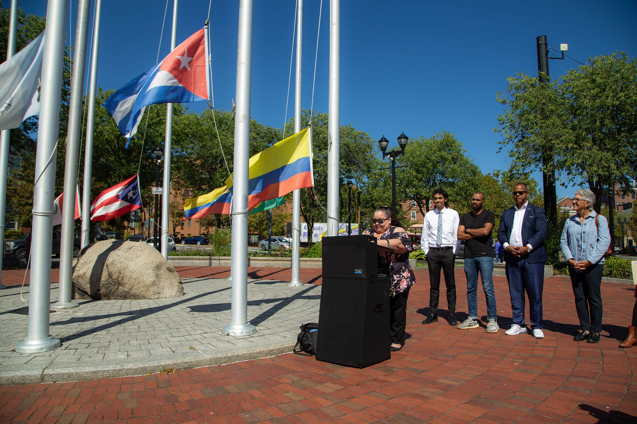 A woman stands behind the podium to speak during the Latinx heritage month flag raising