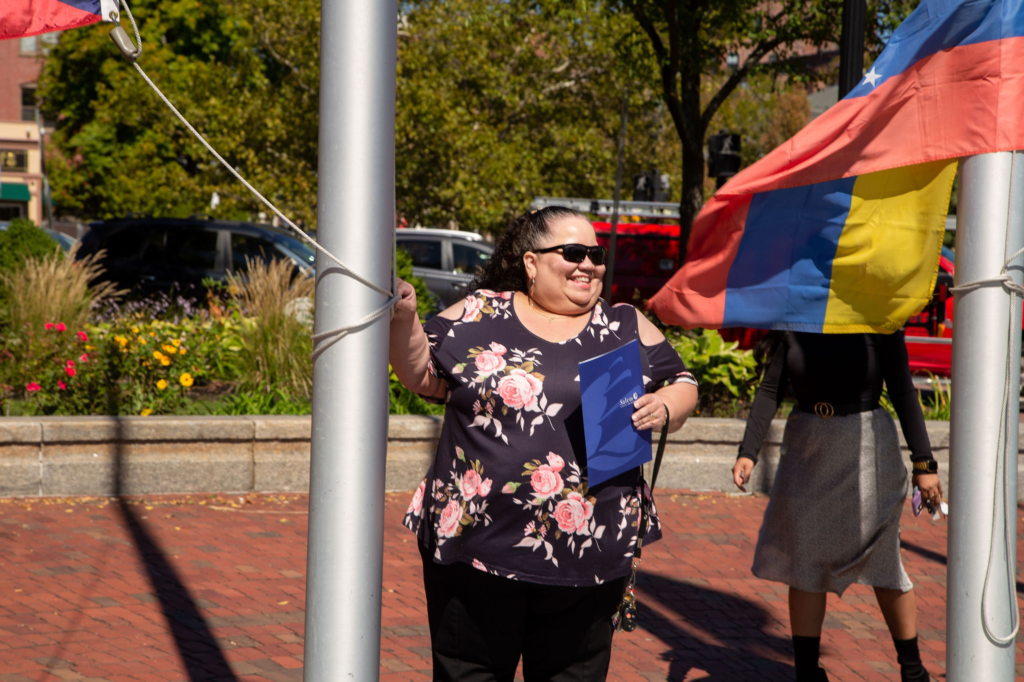 A Latina woman holds the rope holding a flag during the Latinx heritage month flag raising