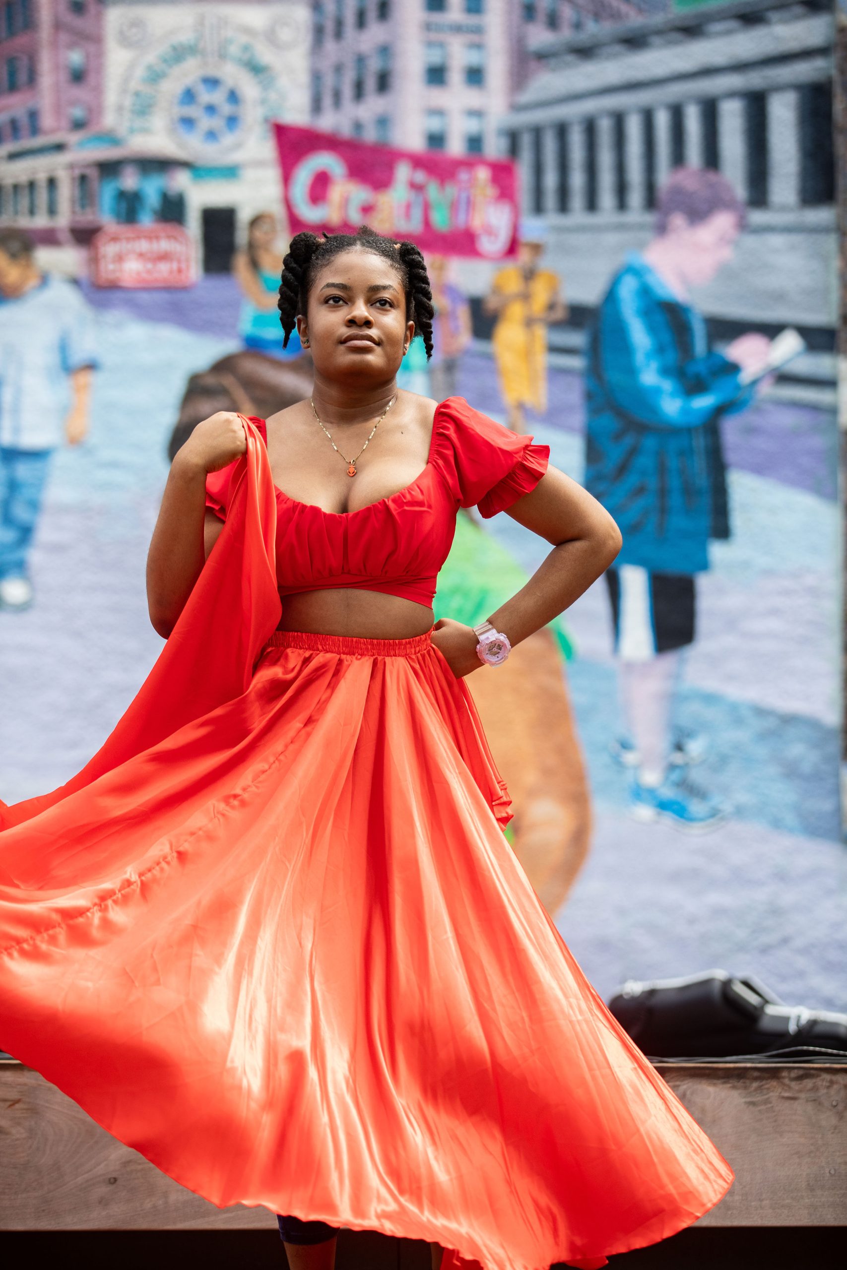 A young woman of color wears a red dress and dances at Lynnside out
