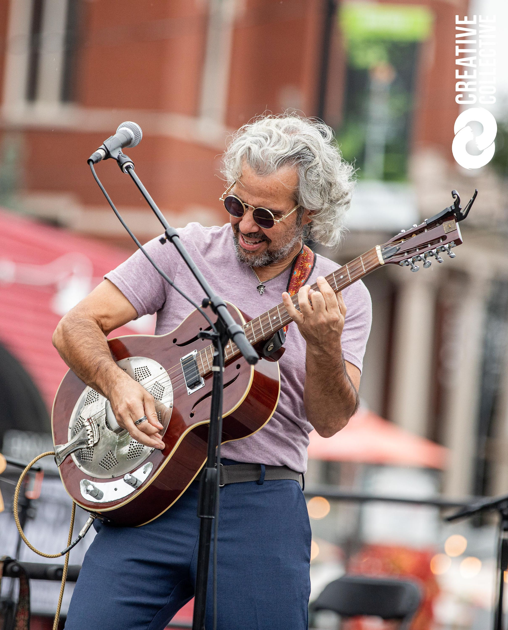 a man with grey hair plays a guitar on stage at the Peabody International Festival