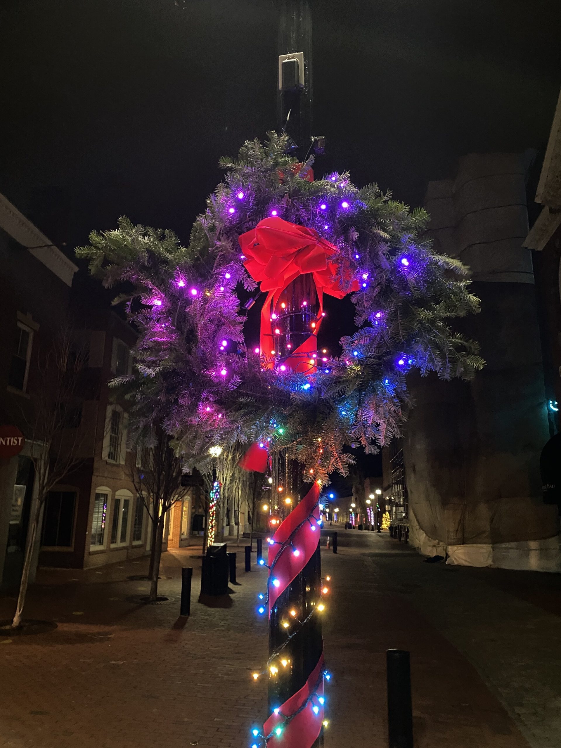 a christmas wreath on a pole with lights around it.
