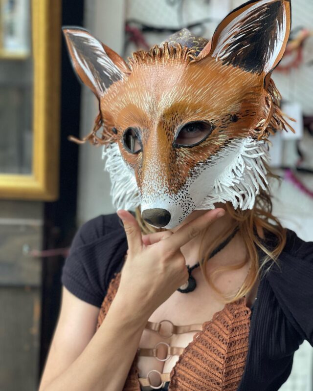 a woman wearing a fox mask in a room.