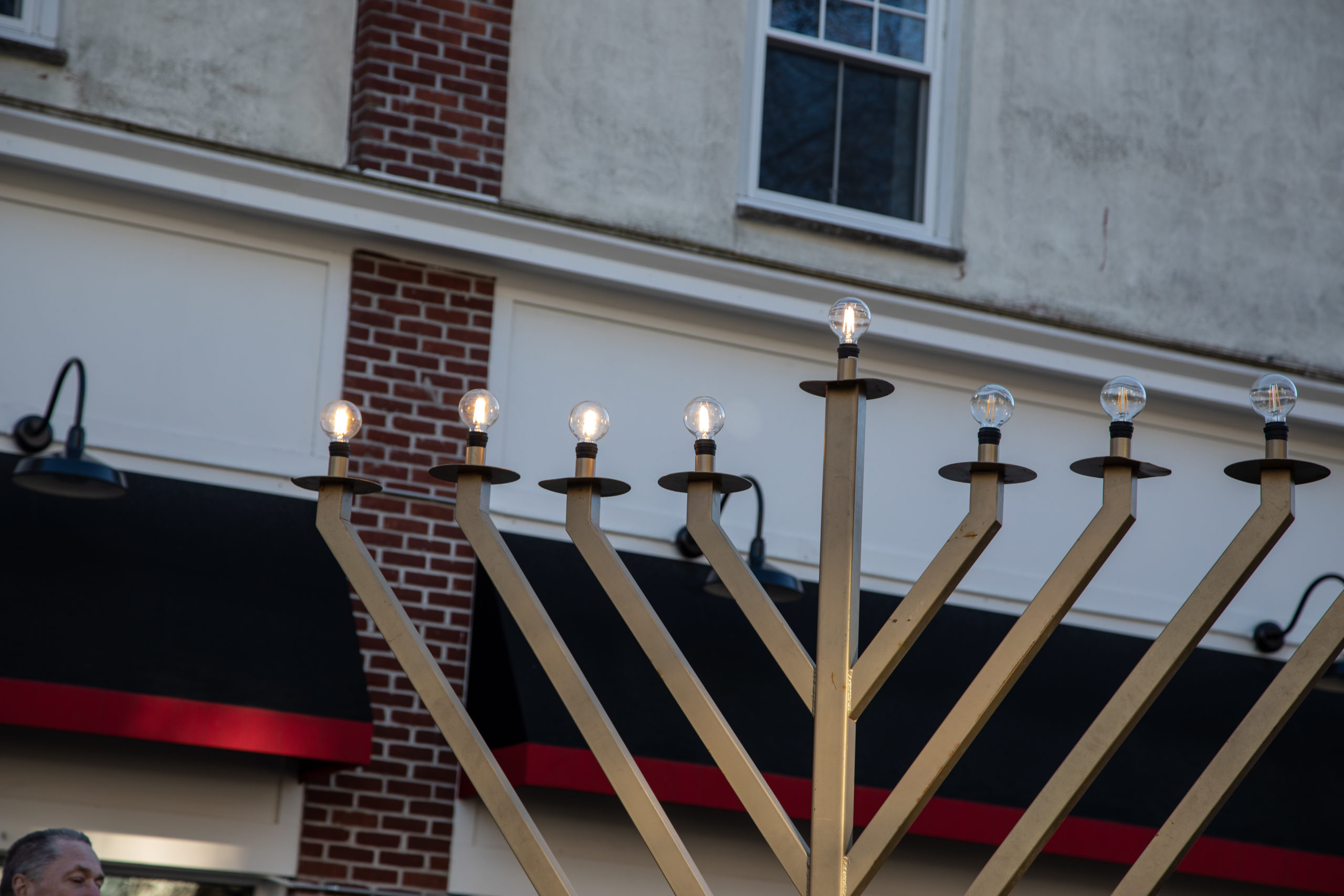 a large menorah with lit candles in front of a store.