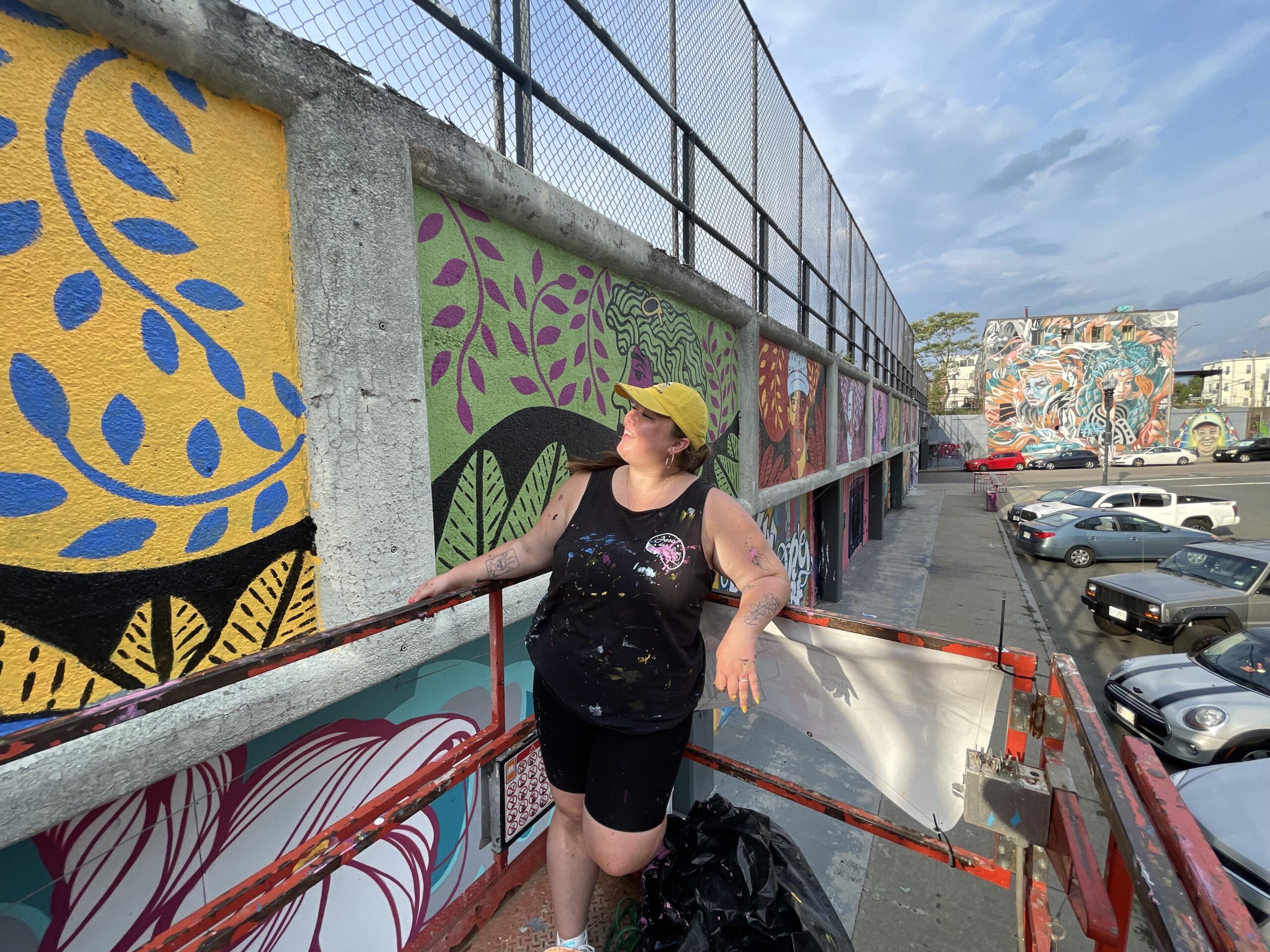a woman leaning on a fence next to a mural.