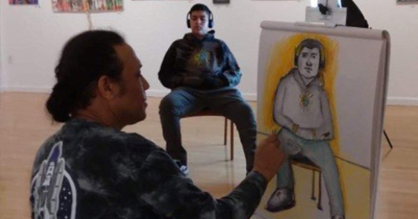 a man sitting in front of a drawing of a man.