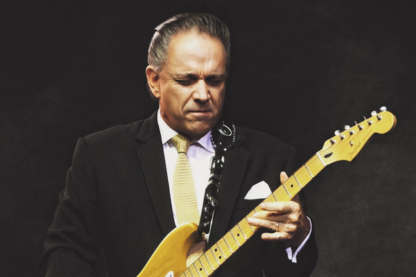 a man in a suit playing a yellow guitar.