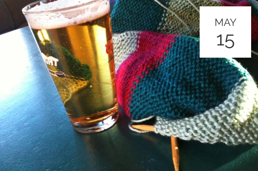 a knitted hat next to a glass of beer.