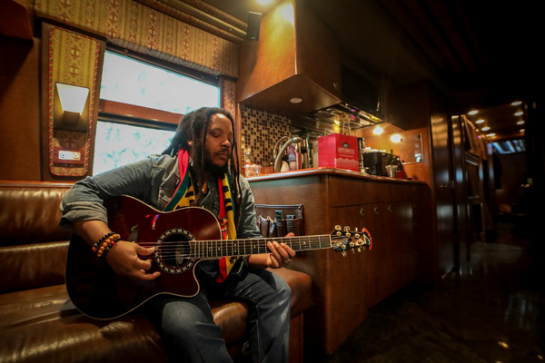 a man with dreadlocks playing a guitar.