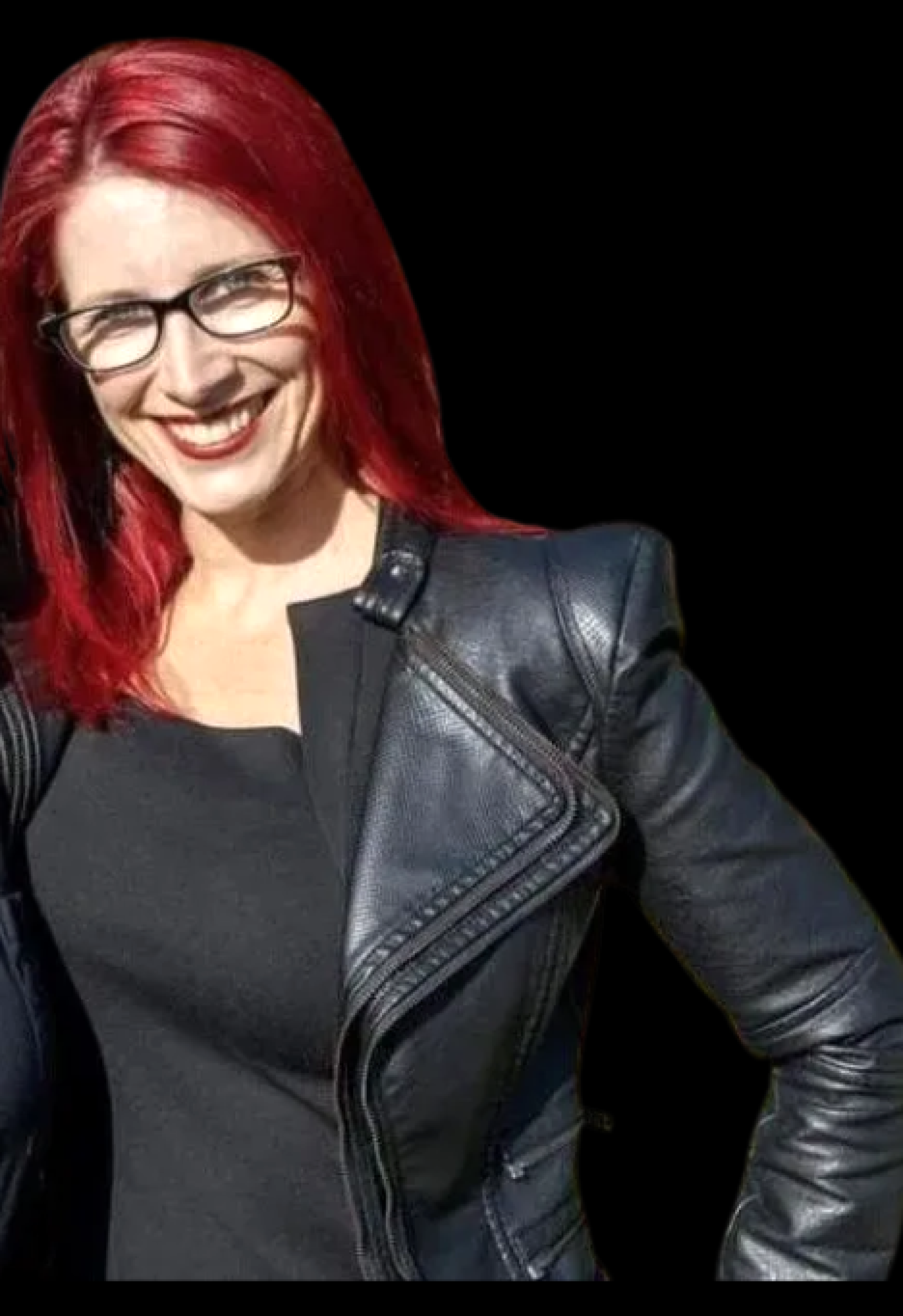 a woman with red hair and glasses is smiling.