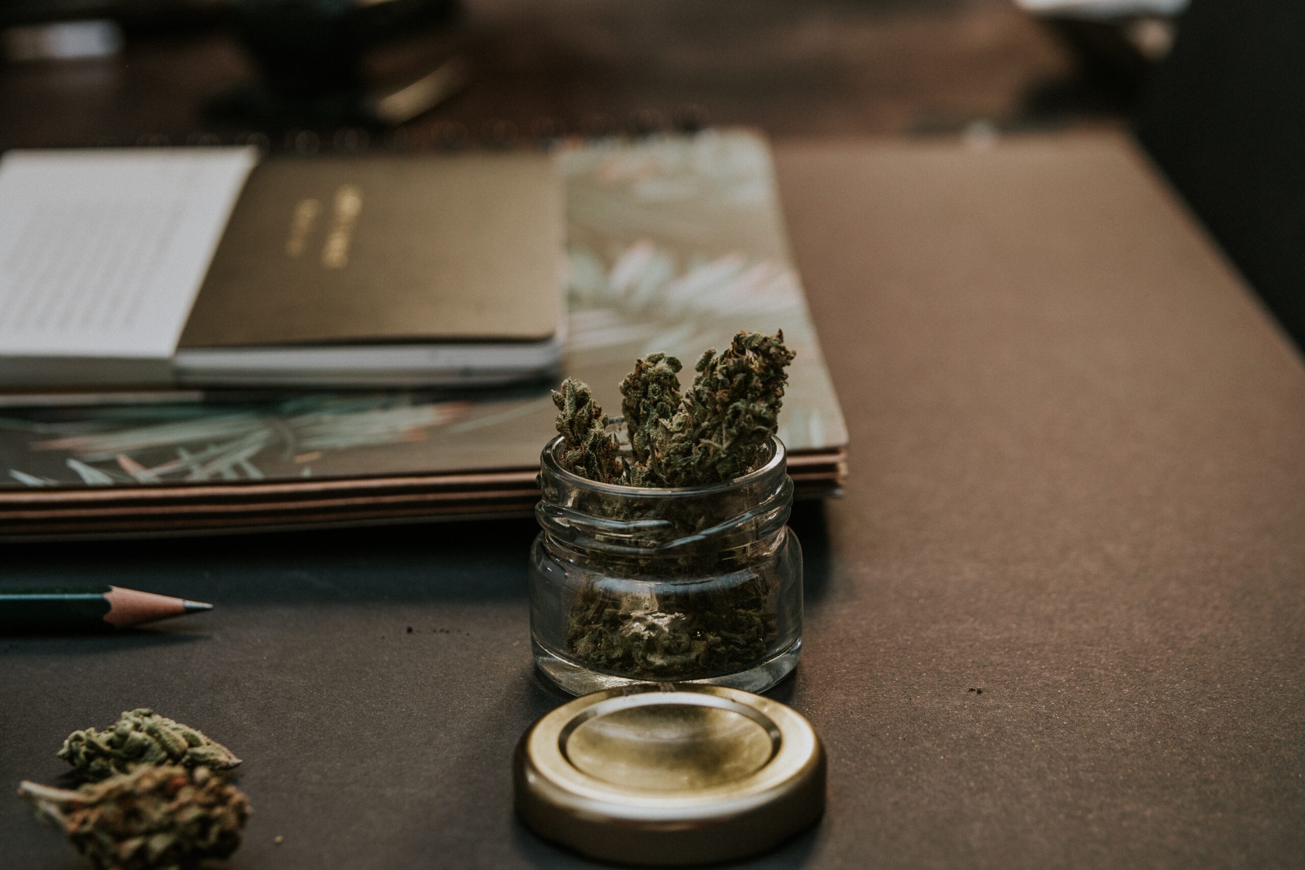 a glass jar filled with marijuana sitting on top of a table.