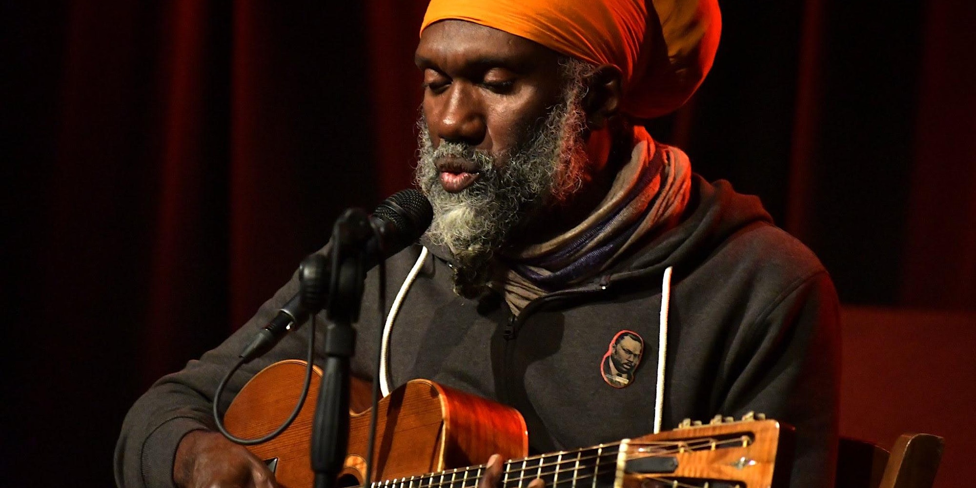 a man with an orange turban playing a guitar.