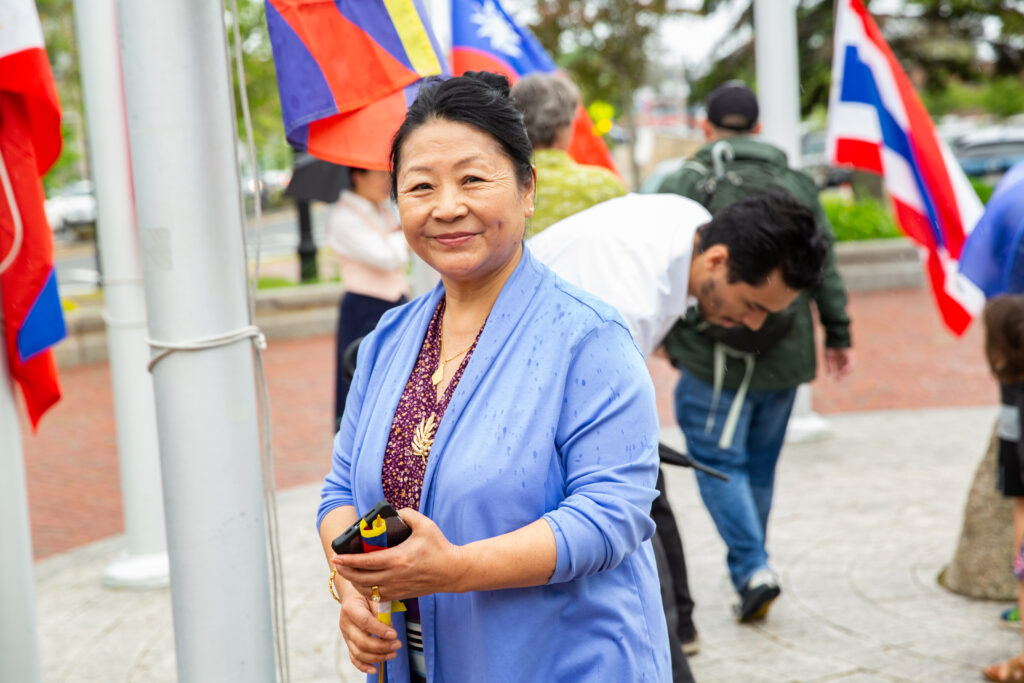a woman standing next to a pole with flags on it.