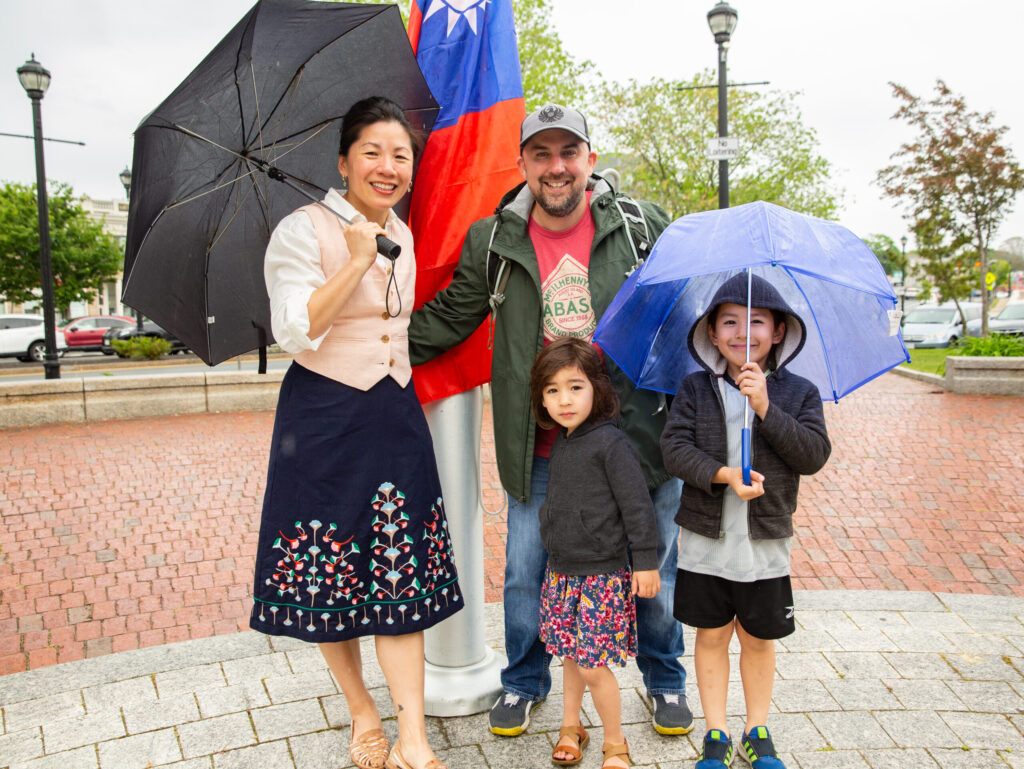 a group of people standing next to each other holding umbrellas.