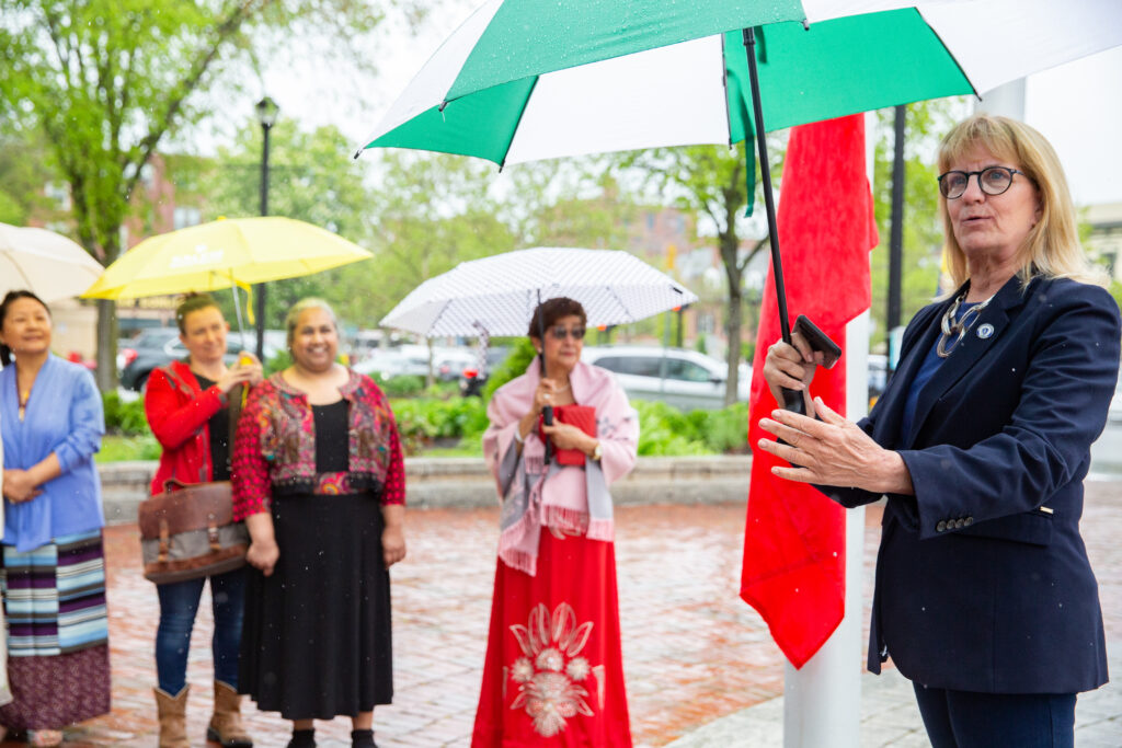 a group of women standing around each other holding umbrellas.
