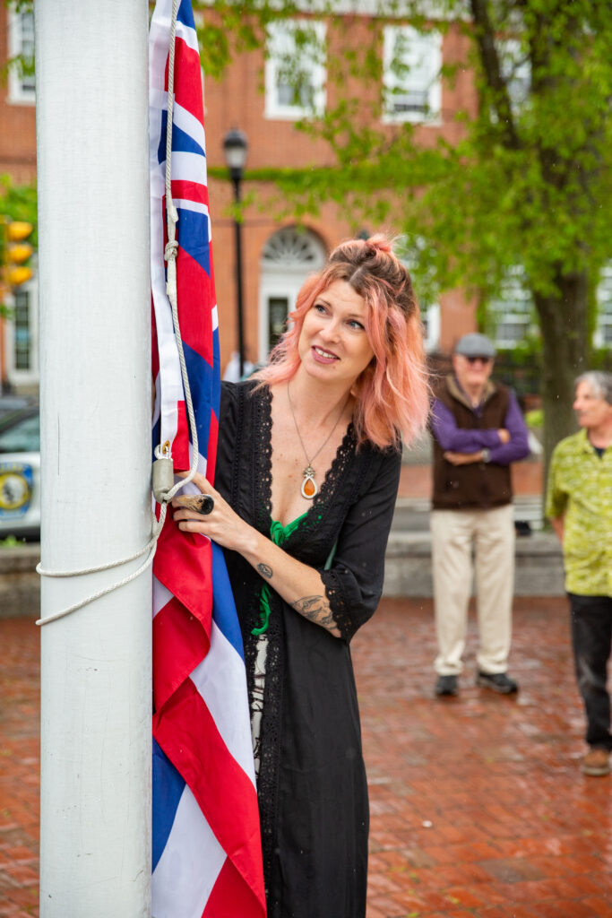 a woman leaning against a pole with a flag on it.