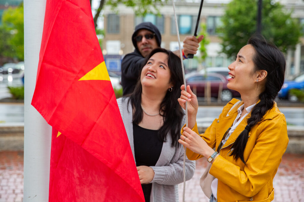 a group of people standing around a red and yellow flag.