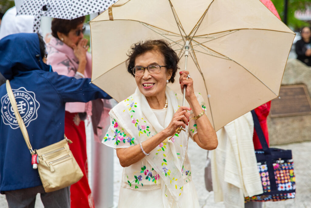 a woman holding an umbrella while standing next to other people.