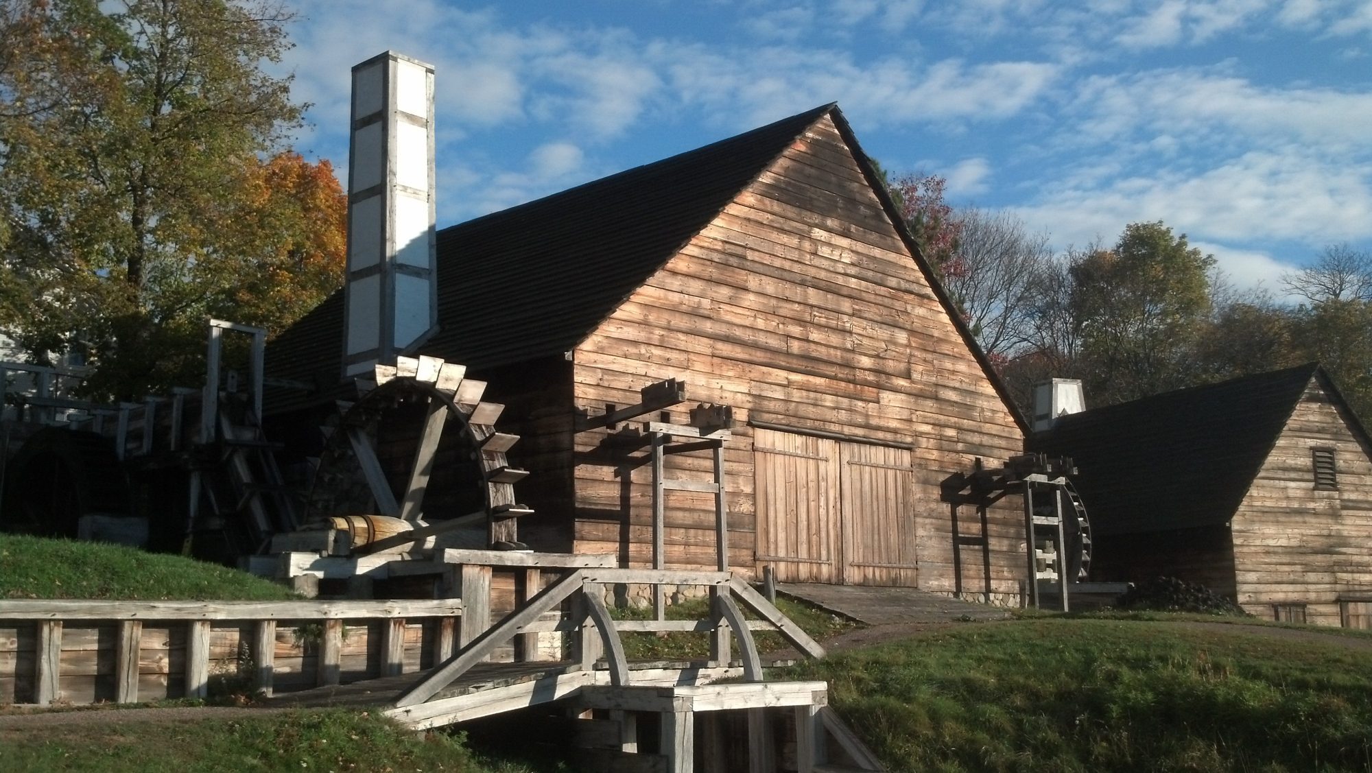 an old wooden building with a water wheel in front of it.