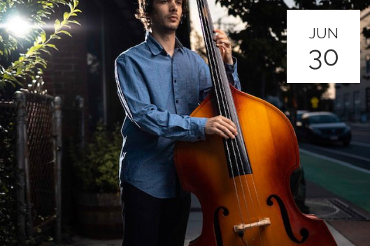 a man holding a cello on a city street.