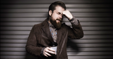 a man with a beard holding a cup of coffee.