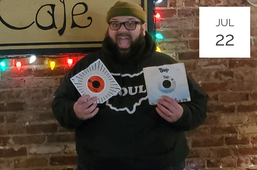 a man with a beard holding up two cds.