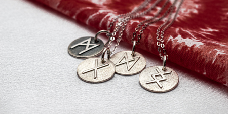three silver necklaces with symbols on them.