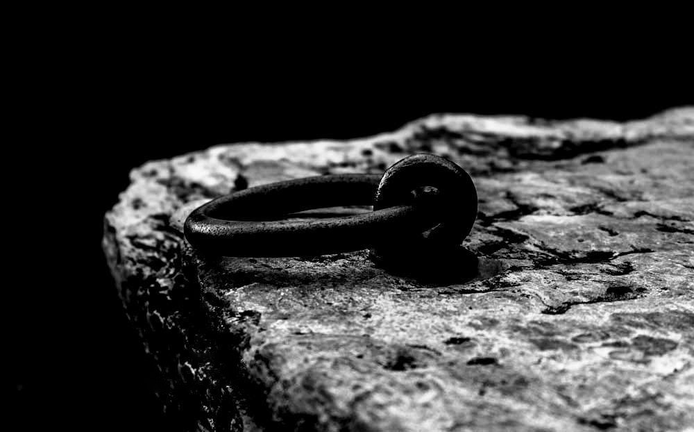 a black and white photo of a ring on a rock.