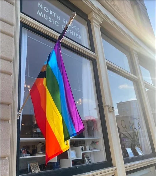 a rainbow flag hanging outside of a store window.