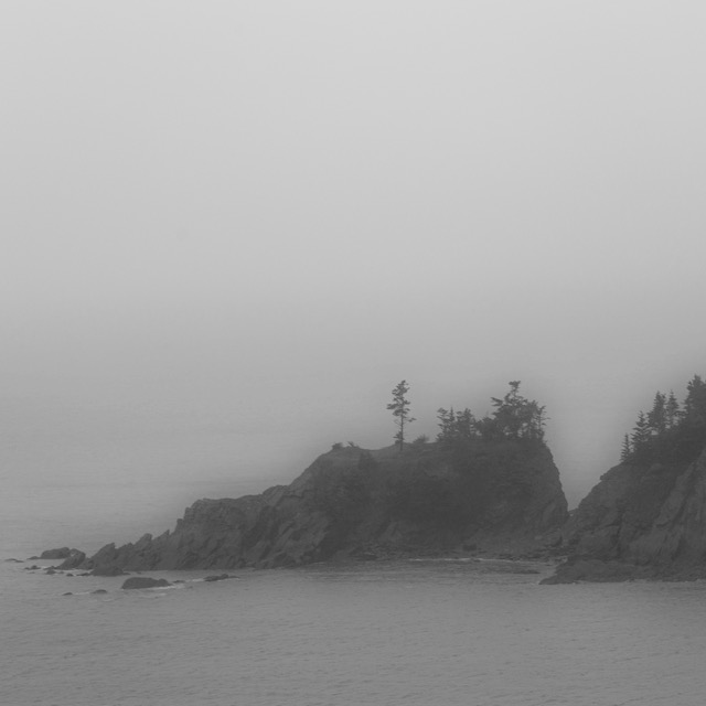 a black and white photo of a lighthouse on a foggy day.