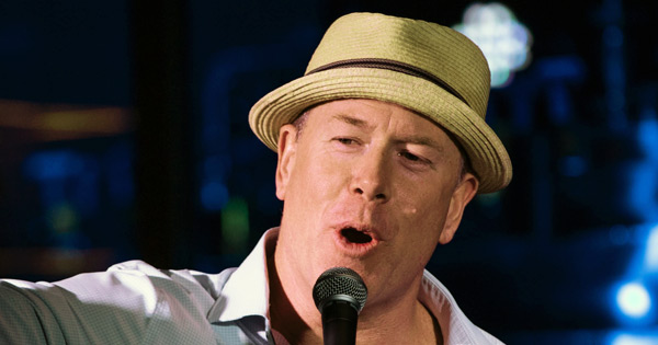 a man in a hat singing into a microphone.