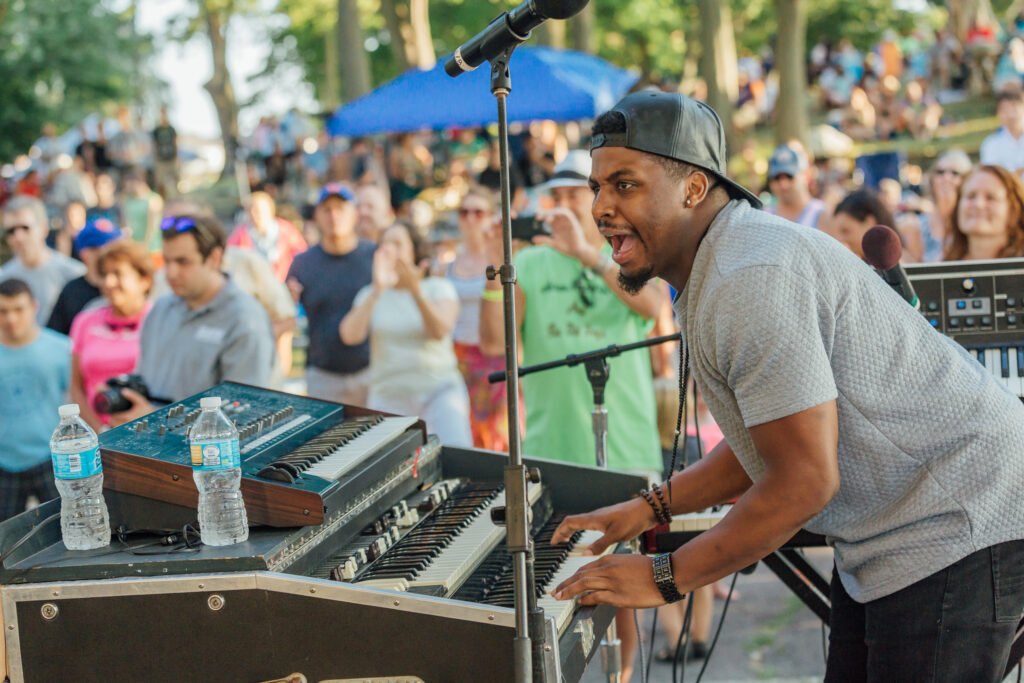 A man playing an electronic keyboard in front of a crowd.