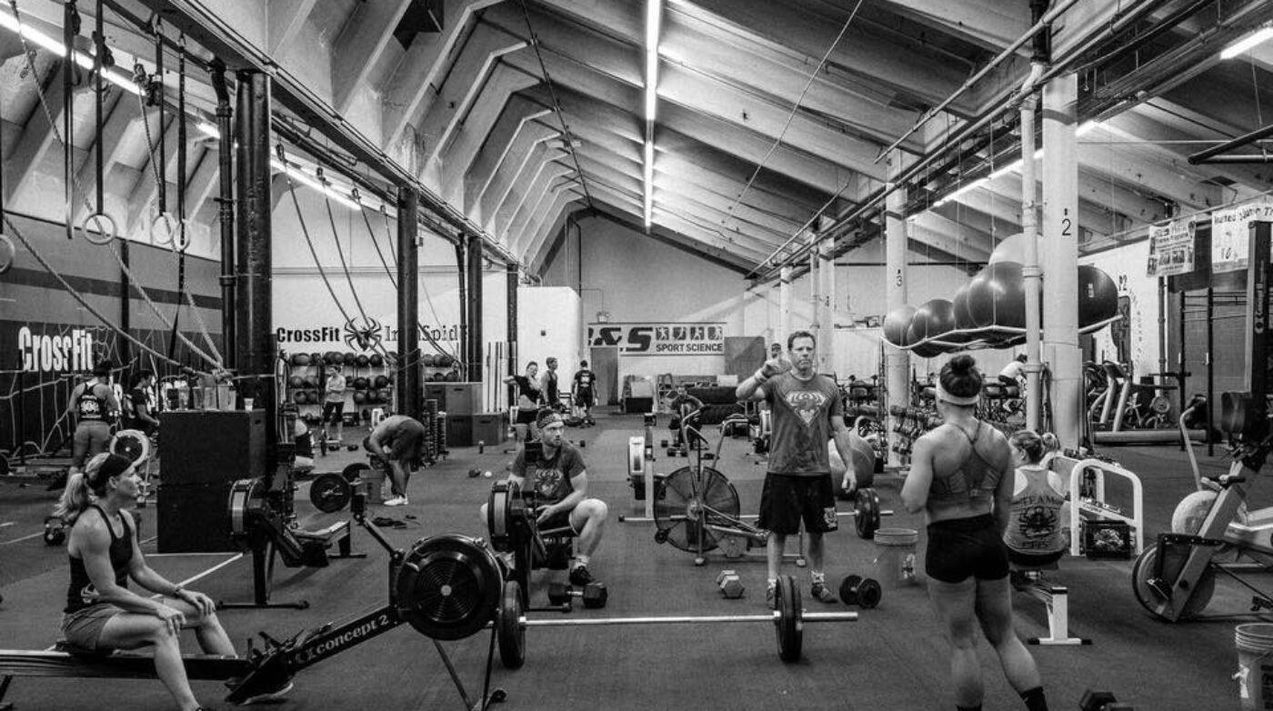 A black and white photo of people in a gym.