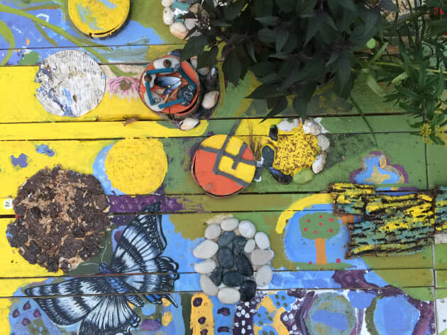 a colorful painting of butterflies and plants on a wooden pallet.