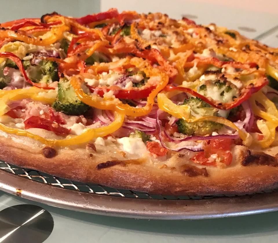 a pizza with vegetables on top of a metal pan.