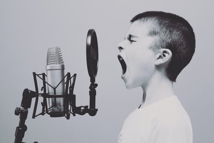 a boy is yelling into a microphone.