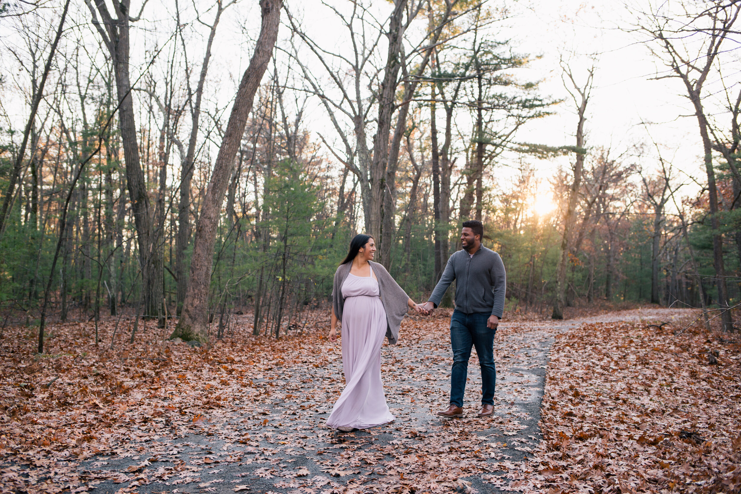 A couple walking through the woods during their maternity session.