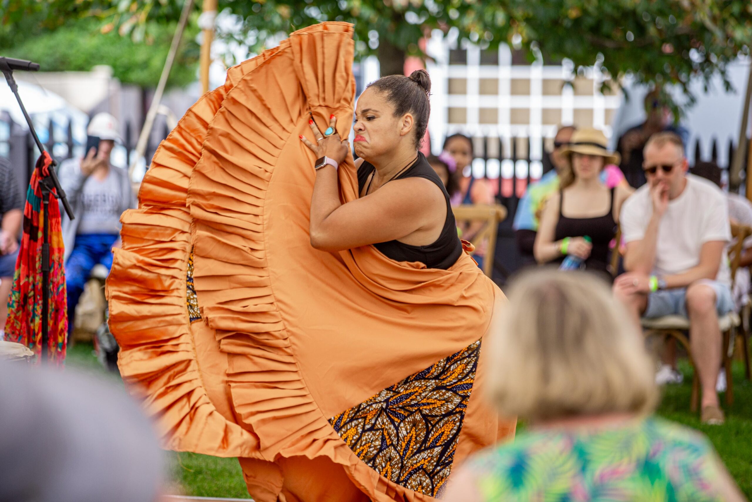 A Puerto Rican Bomba dancer in an orange dress dancing in front of a crowd.