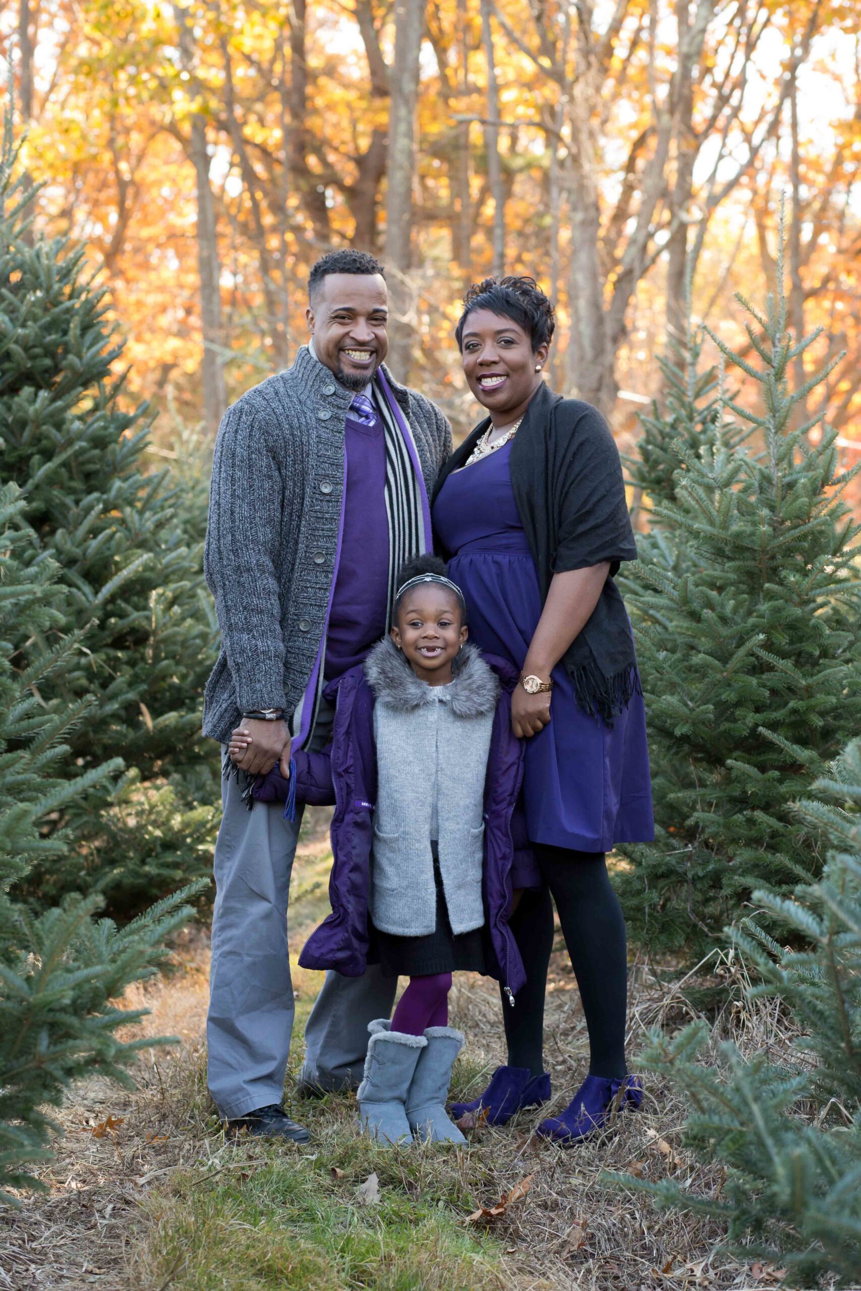 A family posing for a photo in a christmas tree farm.