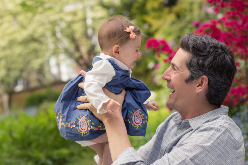 A man holding a baby girl in a garden.