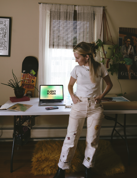 A woman standing in front of a desk with a laptop.