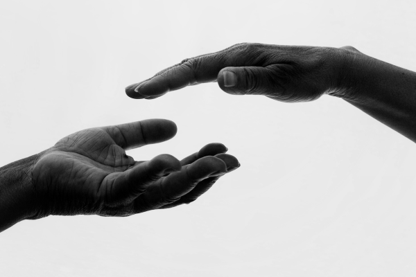 Two hands reaching out to each other in black and white.